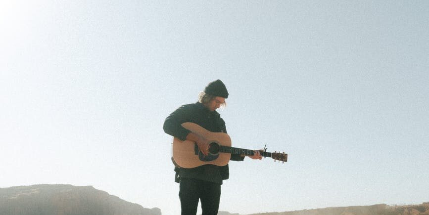 man playing guitar on rough terrain