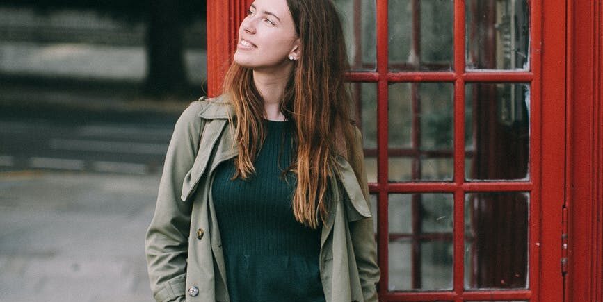 photograph of a woman standing in front of a telephone booth