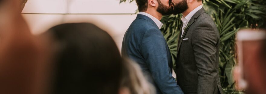 men wearing suit kissing in front of people