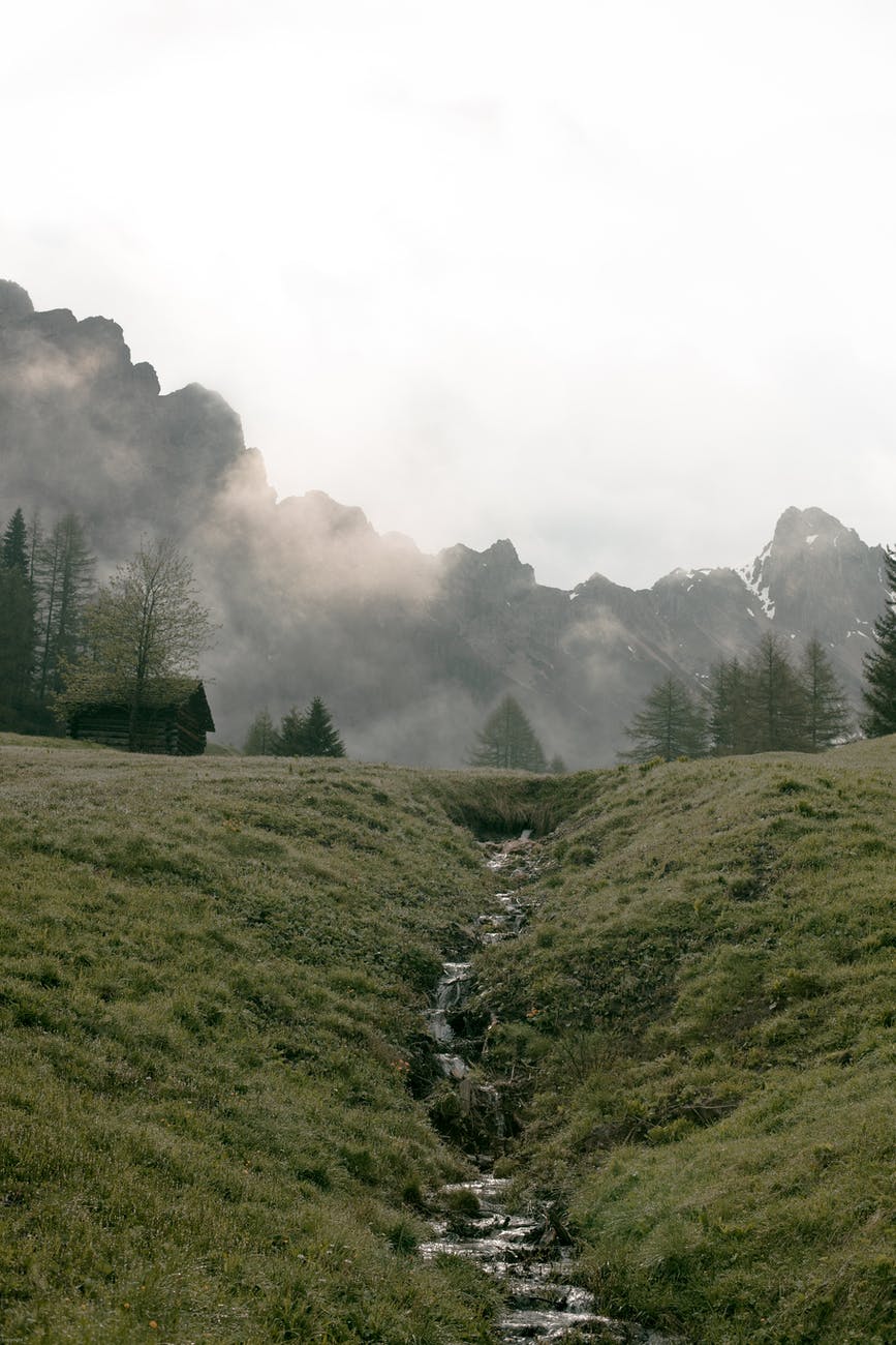 lonesome house on foggy valley against massive mountain ridge