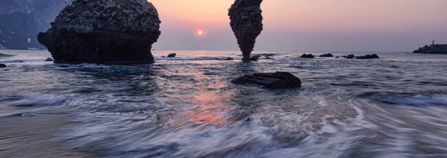 cliffs in sea near coast at sunset