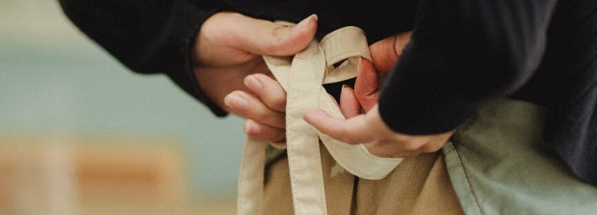 crop faceless woman tying up apron laces