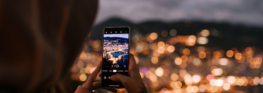 crop unrecognizable person taking photo of night city on smartphone