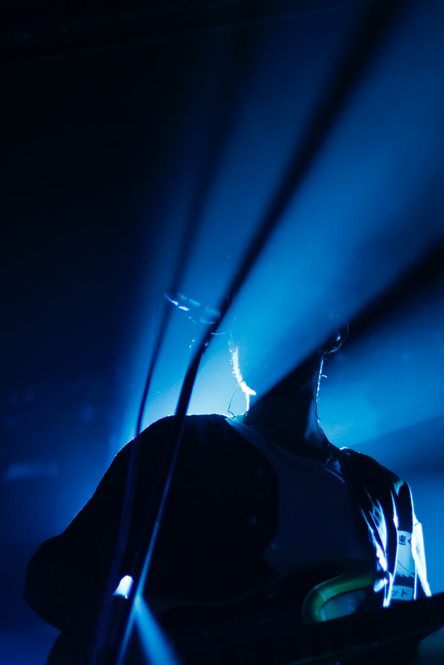 unrecognizable musician singing and playing guitar during concert