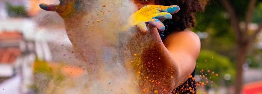 unrecognizable black woman creating colorful dust during holi on embankment