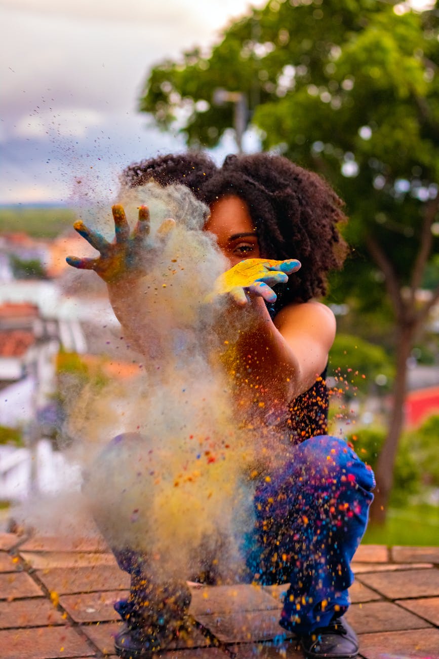 unrecognizable black woman creating colorful dust during holi on embankment