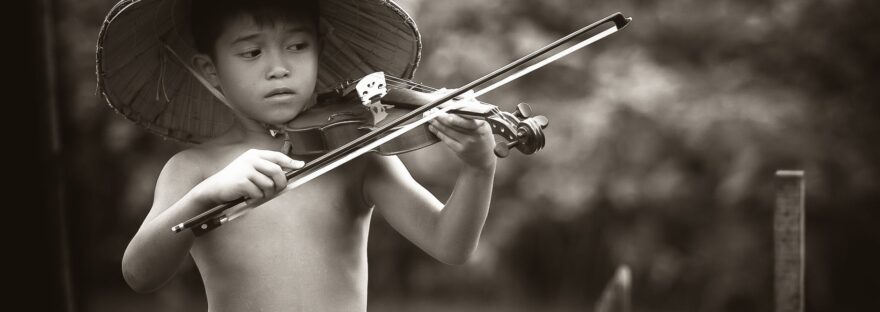 grayscale photography of boy playing violin