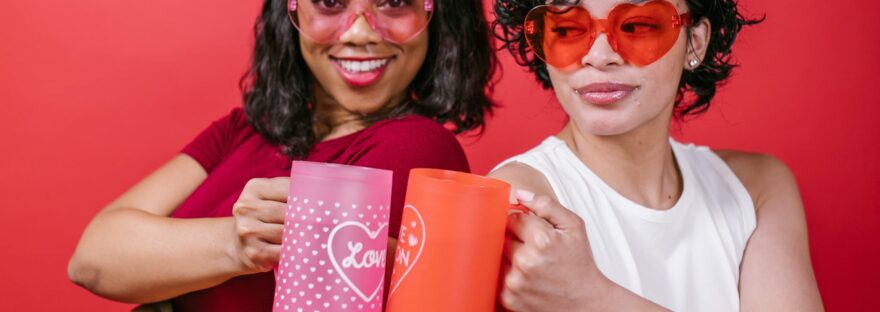 two women holding pink and red mugs