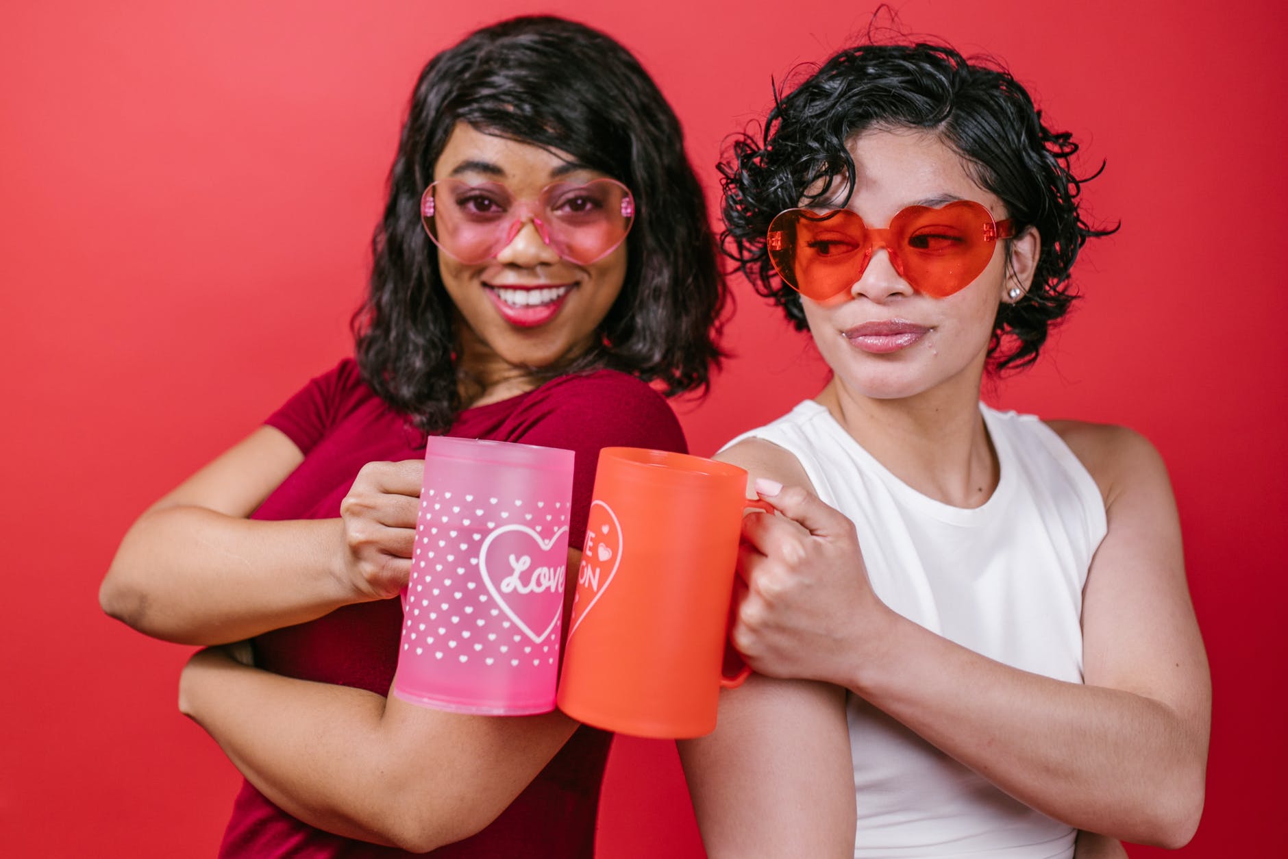 two women holding pink and red mugs