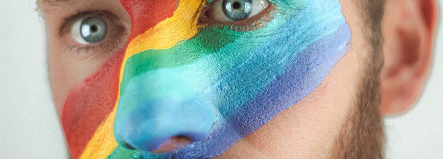 crop young man with lgbt flag painted across face