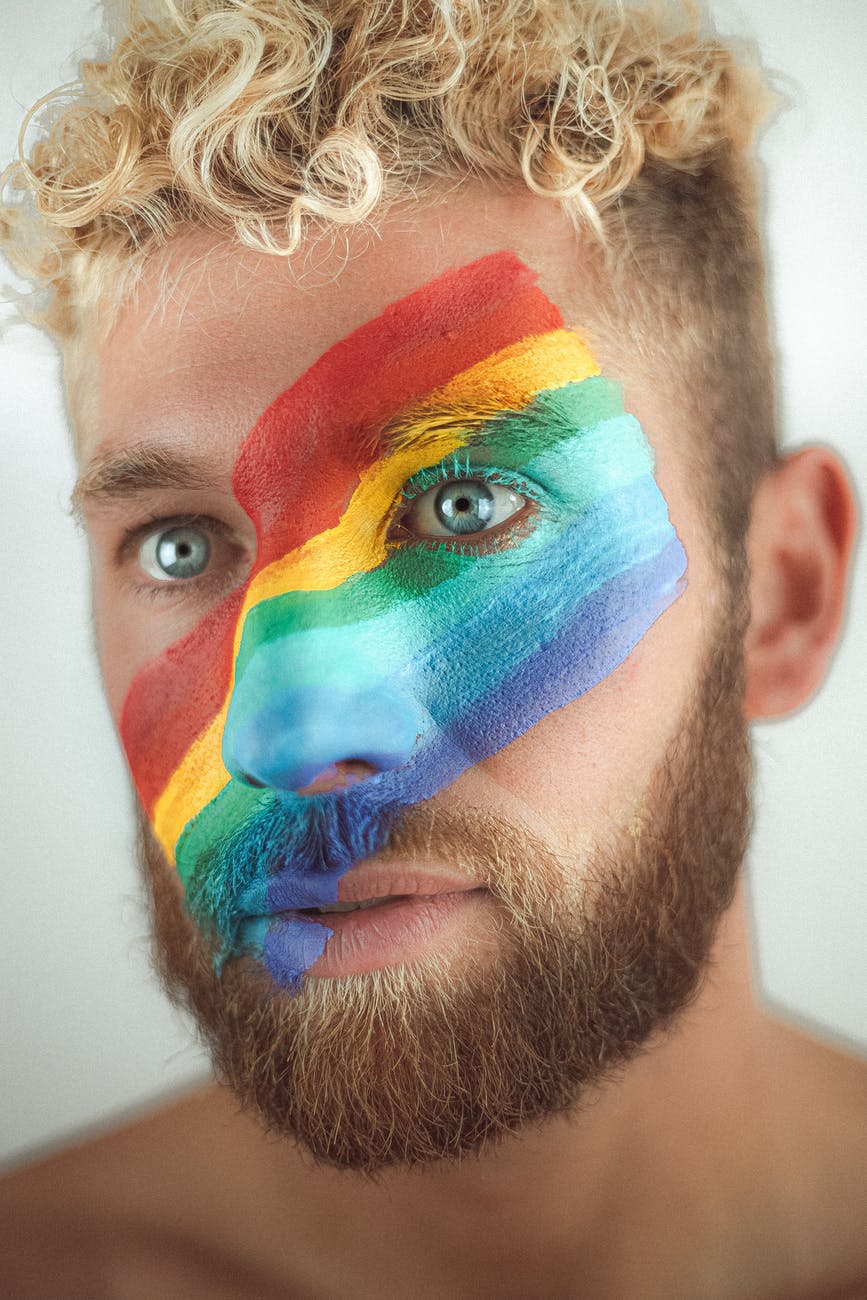 crop young man with lgbt flag painted across face