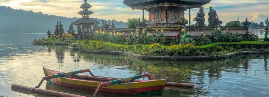 canoe on body of water with pagoda background