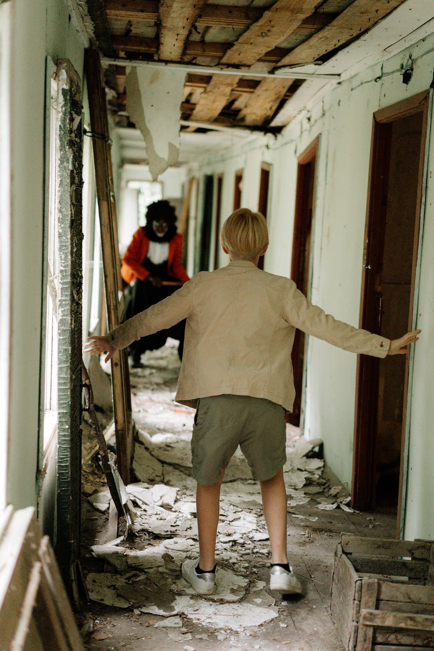 boy in brown t shirt and brown shorts standing on white wooden door