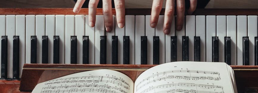 crop pianist playing piano with sheet music on stand