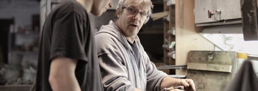 workers handling detail by pneumatic tool in workshop