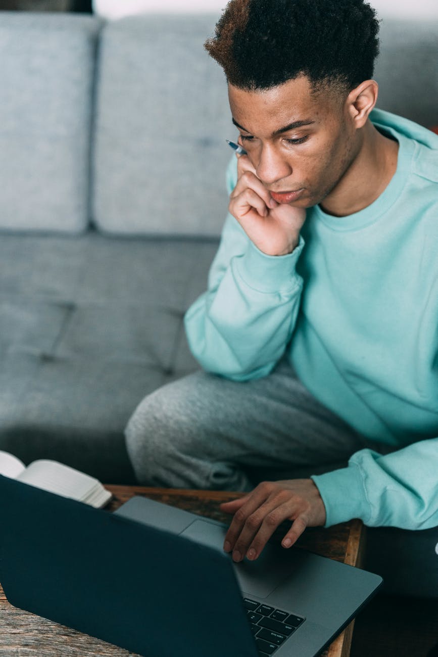serious black man browsing laptop at table
