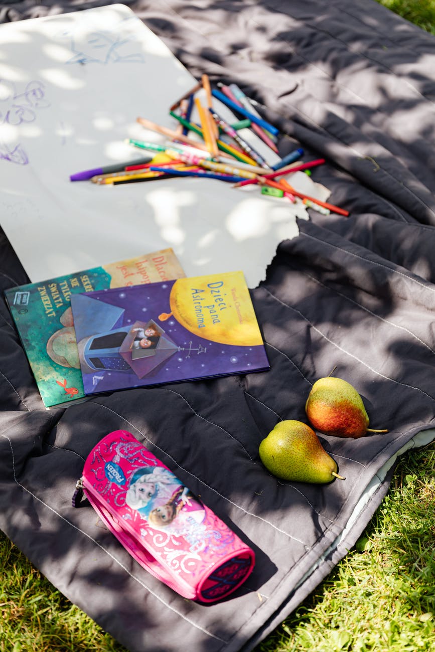 books and colored pens on purple blanket