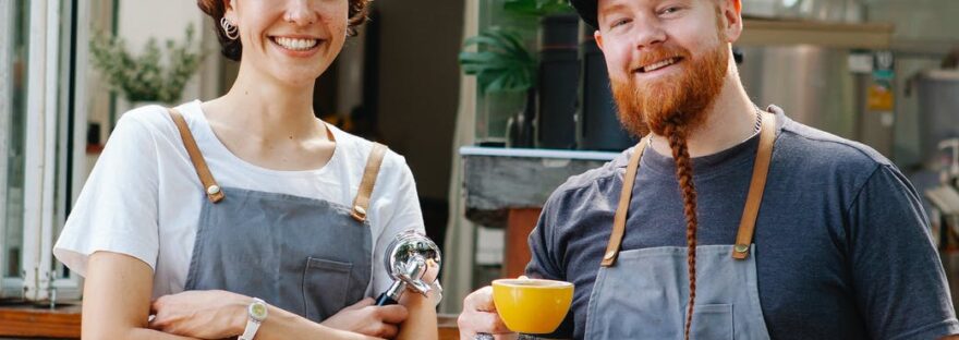 positive coworkers in aprons on terrace of cafe