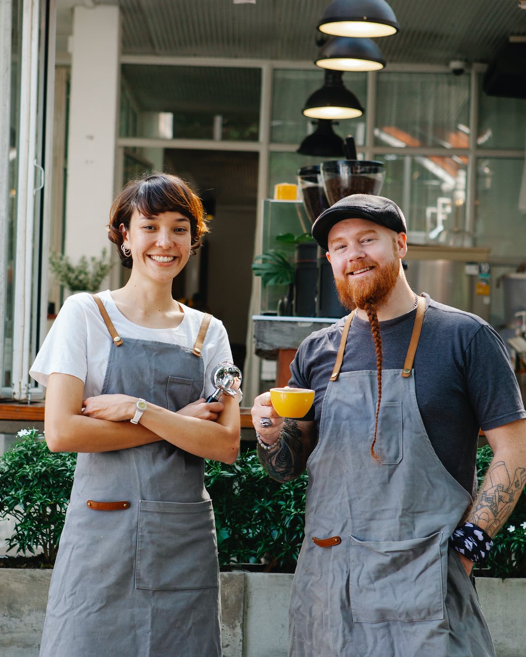 positive coworkers in aprons on terrace of cafe