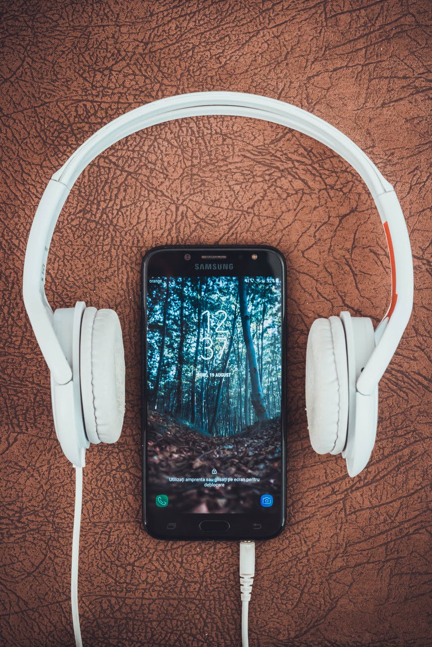 turned on black samsung smartphone between headphones