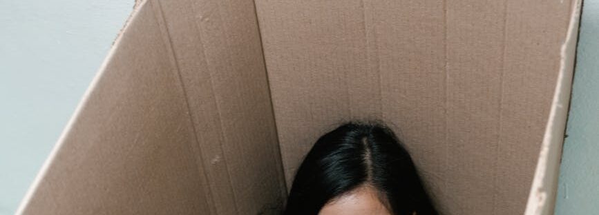a fearful woman having claustrophobia in a cardboard box